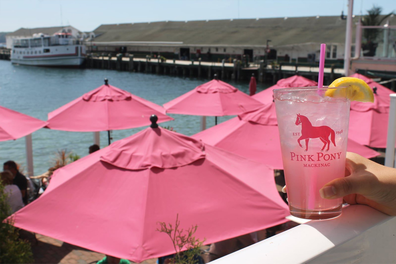 patio of Pink Pony on Mackinac Island showing the harbor, umbrellas and a drink
