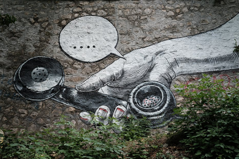 graffiti art on a brick wall of a hand holding phone, a speach bubble above the phone is blank signifying no one is on the other line